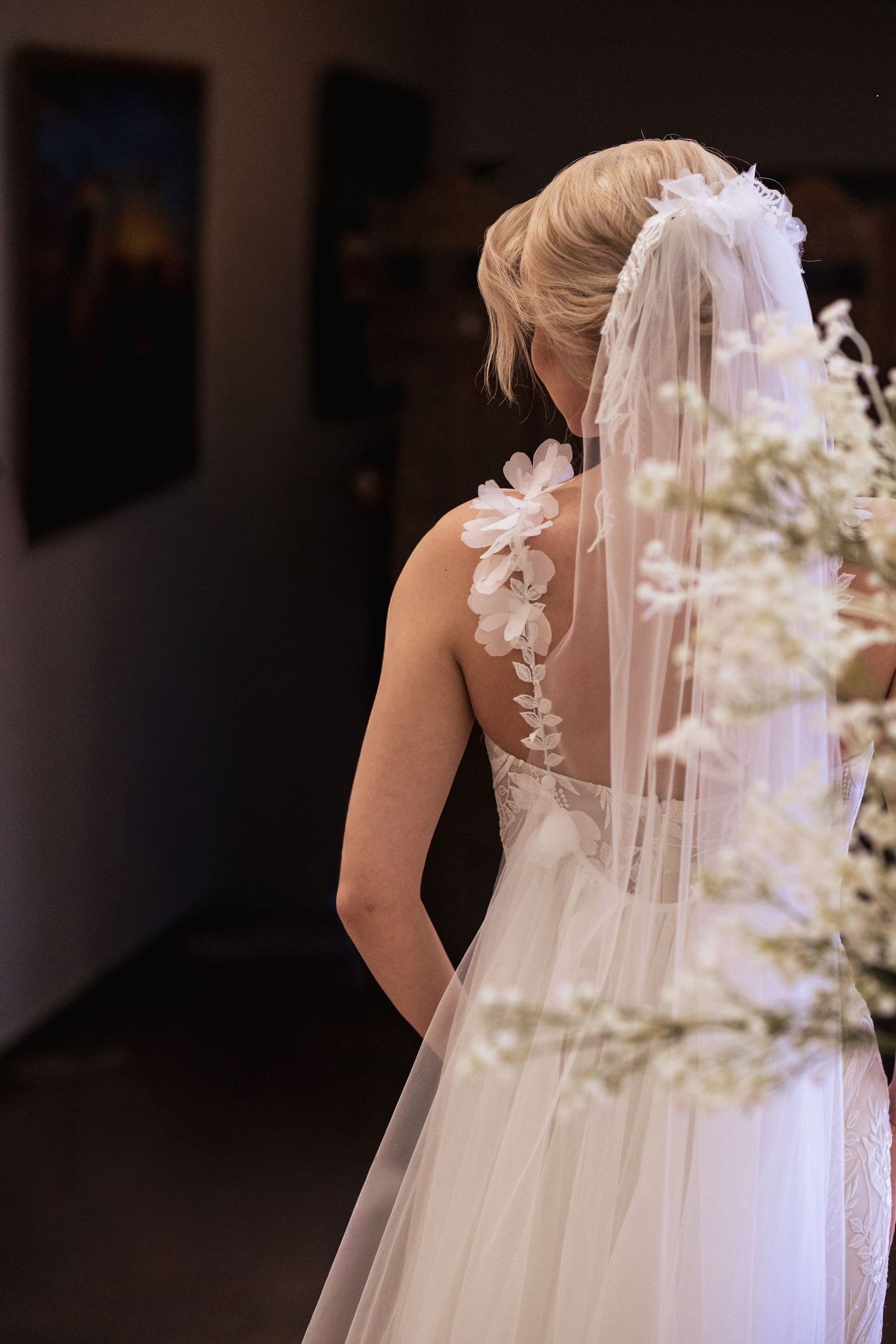 Back view of a wedding dress showing intricate lace details and flowing veil.