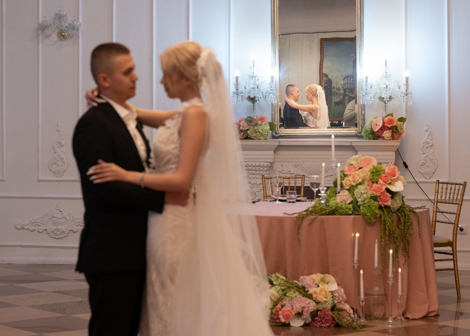 Elegant wedding reception setup with white decor and floral centerpieces in a bright ballroom.