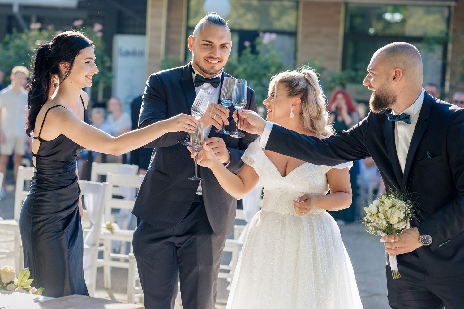 Wedding party toasts with champagne glasses during an outdoor celebration.