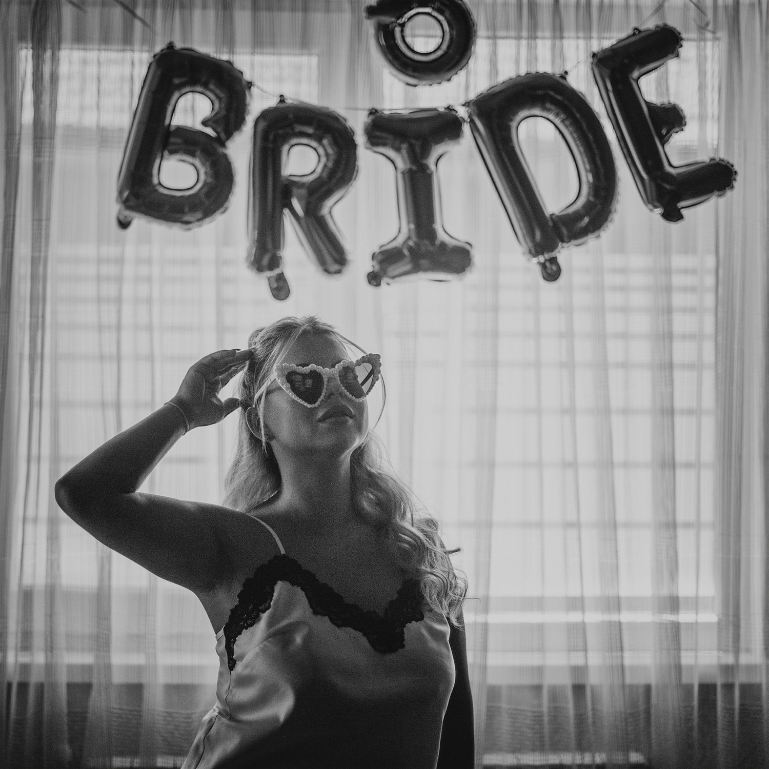 Black and white photo with balloon letters spelling out 'BRIDE' in the background.