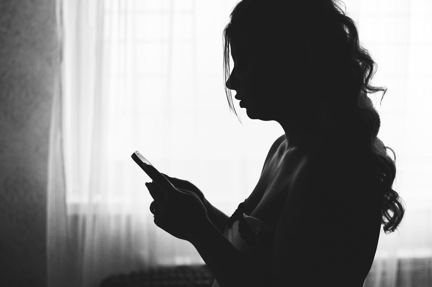 Artistic silhouette portraits in black and white against window light.