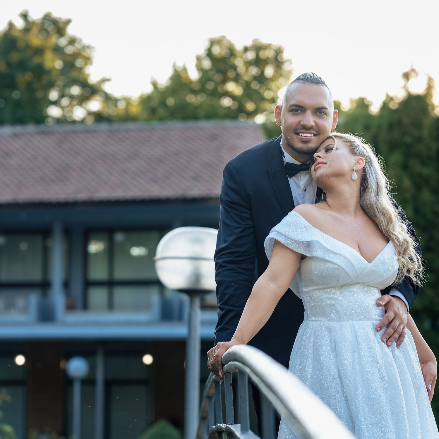 Joyful wedding couple embracing on an outdoor terrace at sunset.