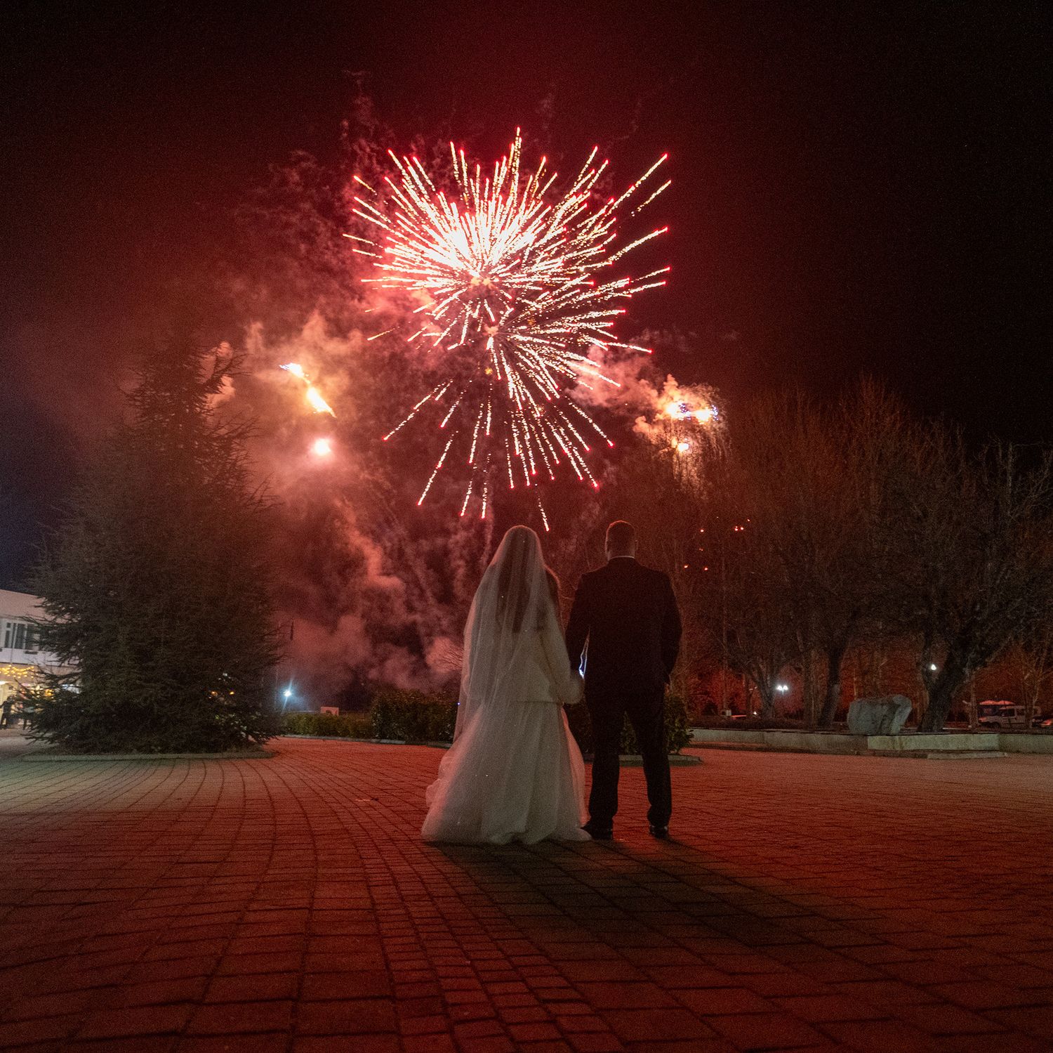 Fireworks illuminate the night sky in vibrant red bursts during a winter celebration.