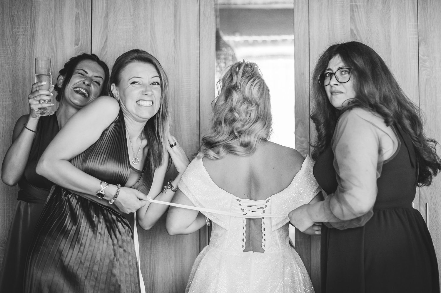 Wedding party sharing laughter and embraces in candid black and white photos.