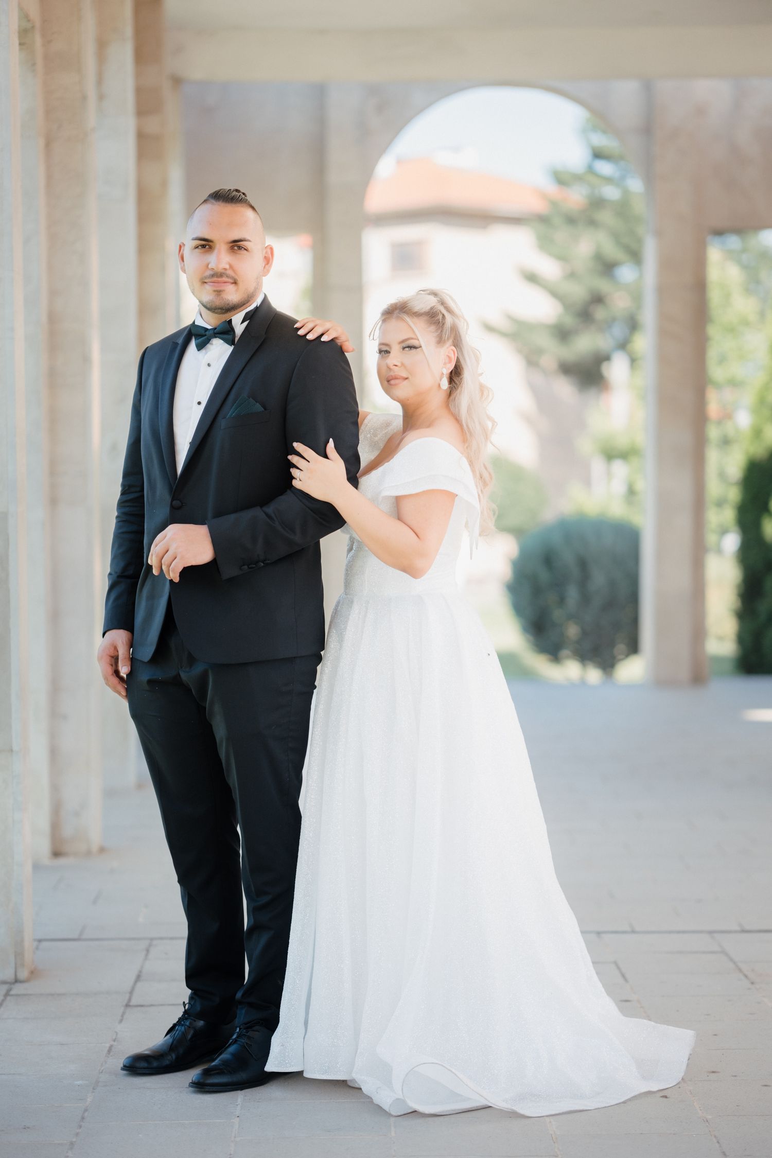 Romantic wedding portraits taken in an elegant colonnade with natural lighting.