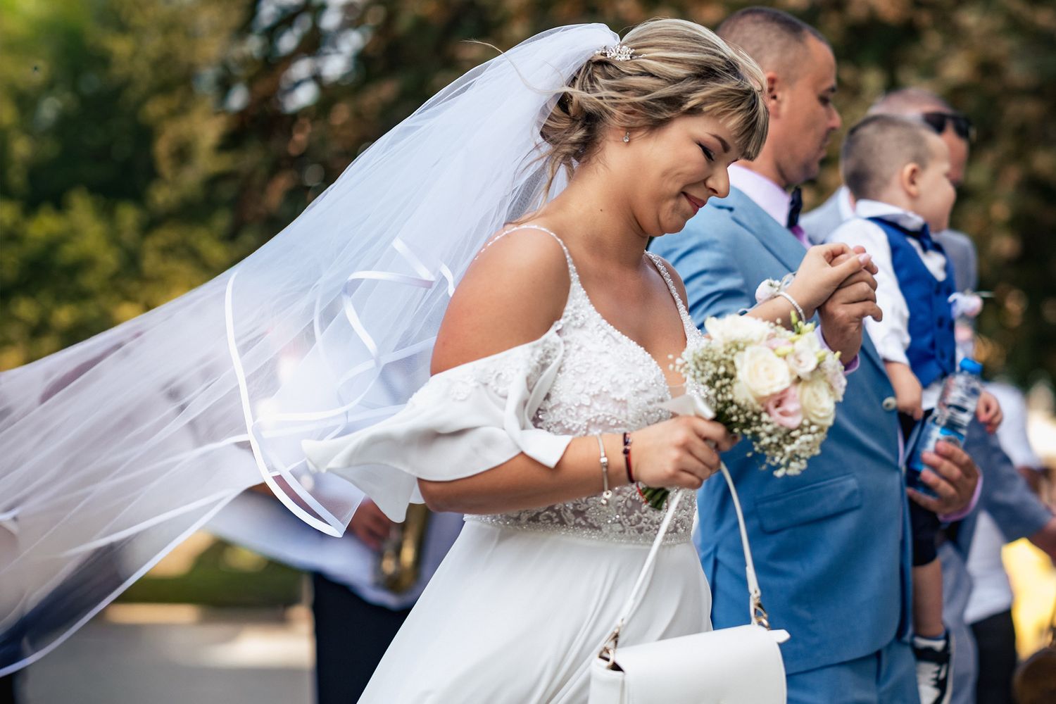 Wedding party members pose with drinks during an outdoor celebration.