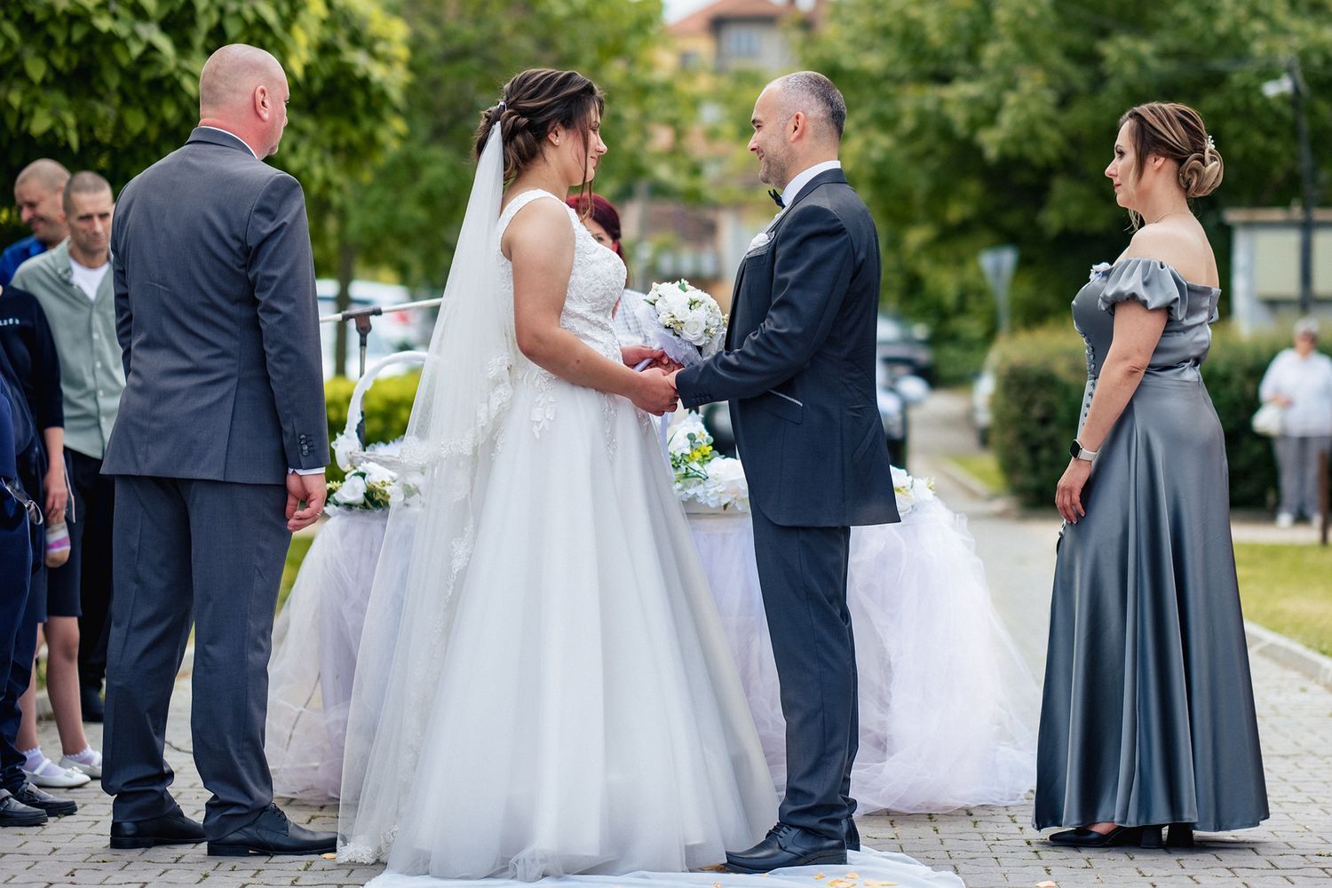 A wedding ceremony taking place outdoors with attendees gathered around.