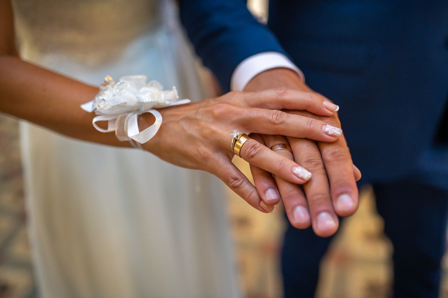 Close-up of hands showing wedding rings and jewelry.