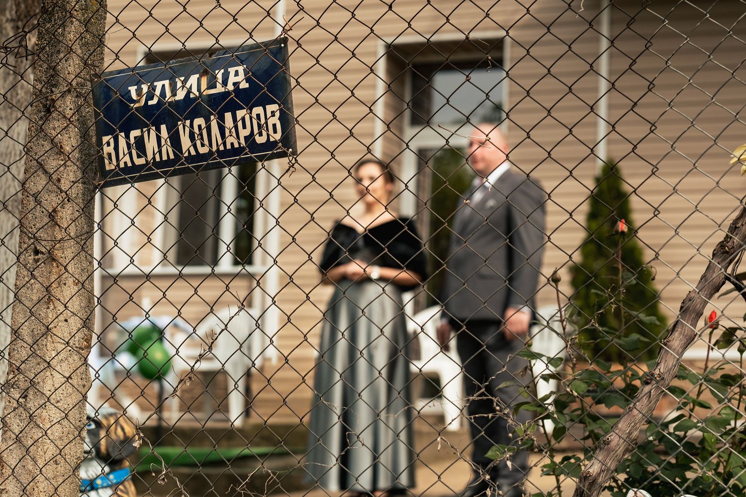Couple posing in front of a rustic building with foreign language signage.