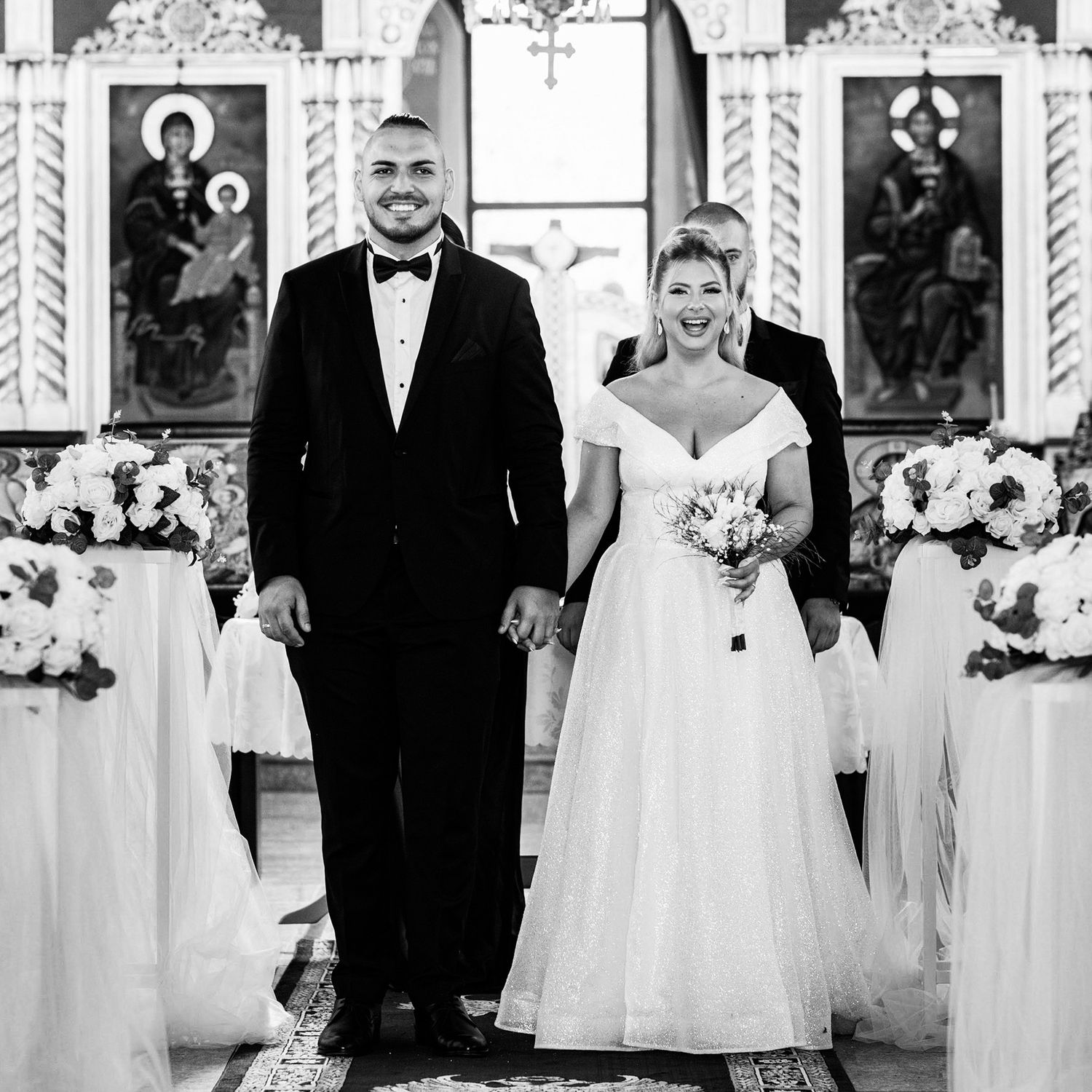 Formal wedding party lineup in front of ornate church backdrop.