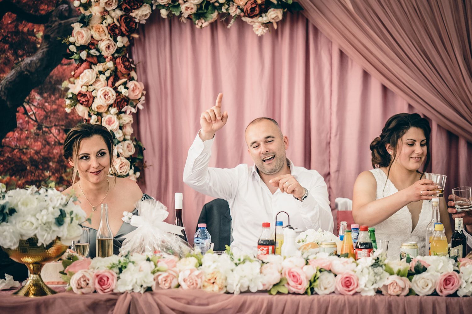 Wedding reception table decorated with pink draping and floral arrangements.