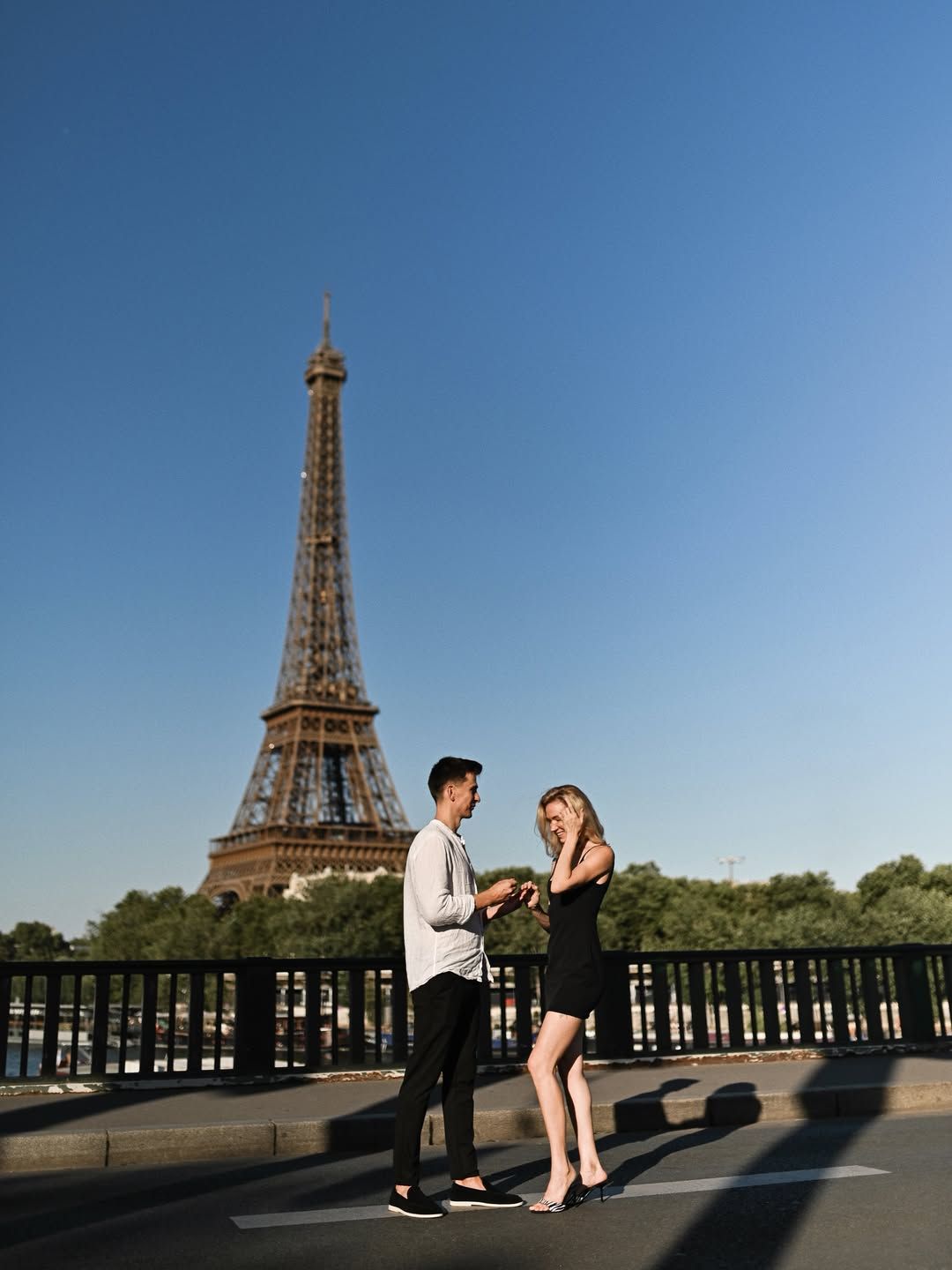 A surprise proposal photographer in Paris captured this standing engagement moment on Pont de Bir-Hakeim under a blue sky.