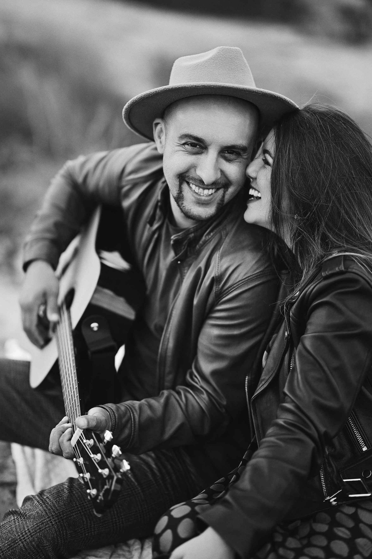 Future groom playing guitar for his fiancée during a romantic seaside engagement session in Valencia