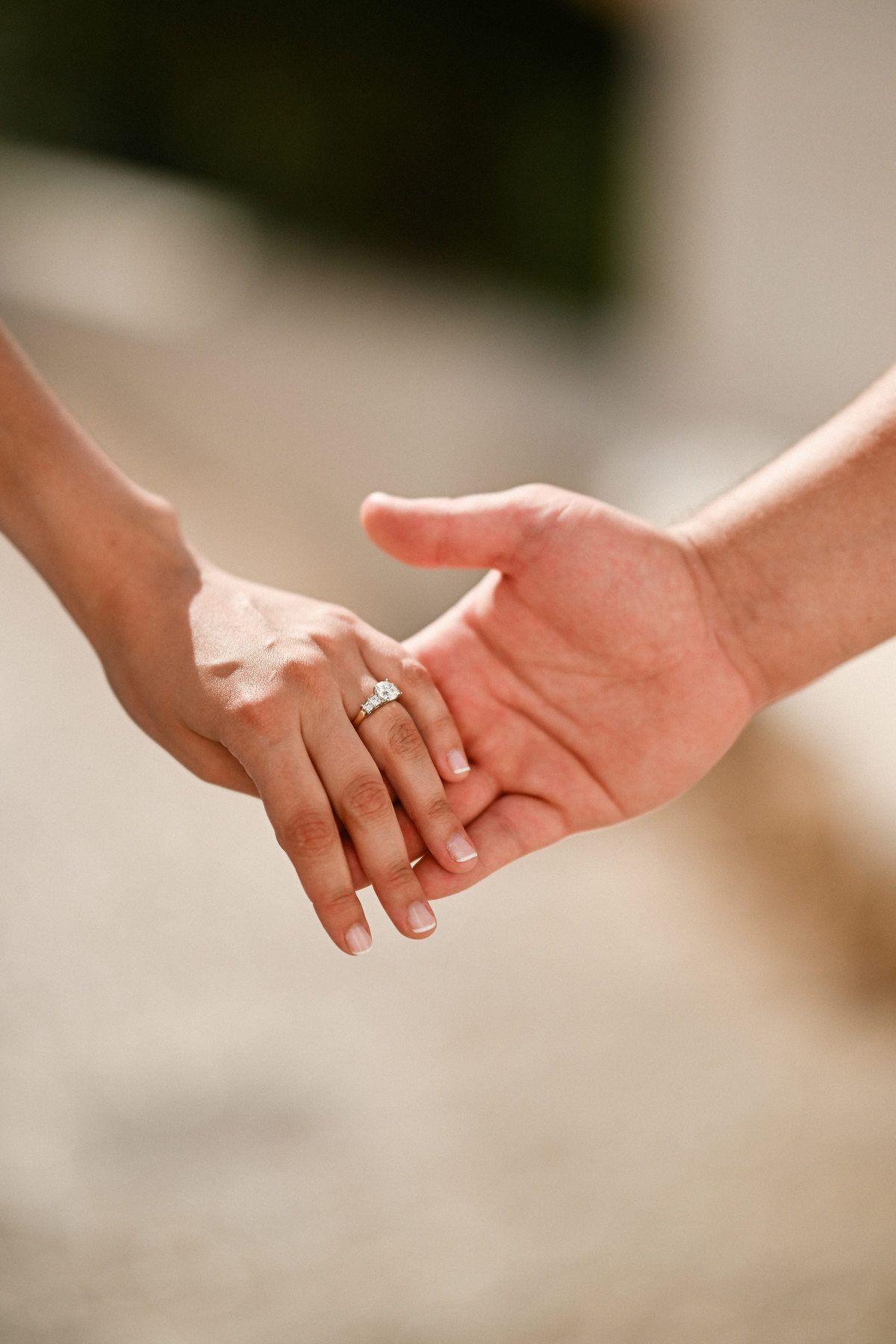 Close-up of a woman's hand wearing a new ring while holding her partner's hand after a secret proposal in Altea.