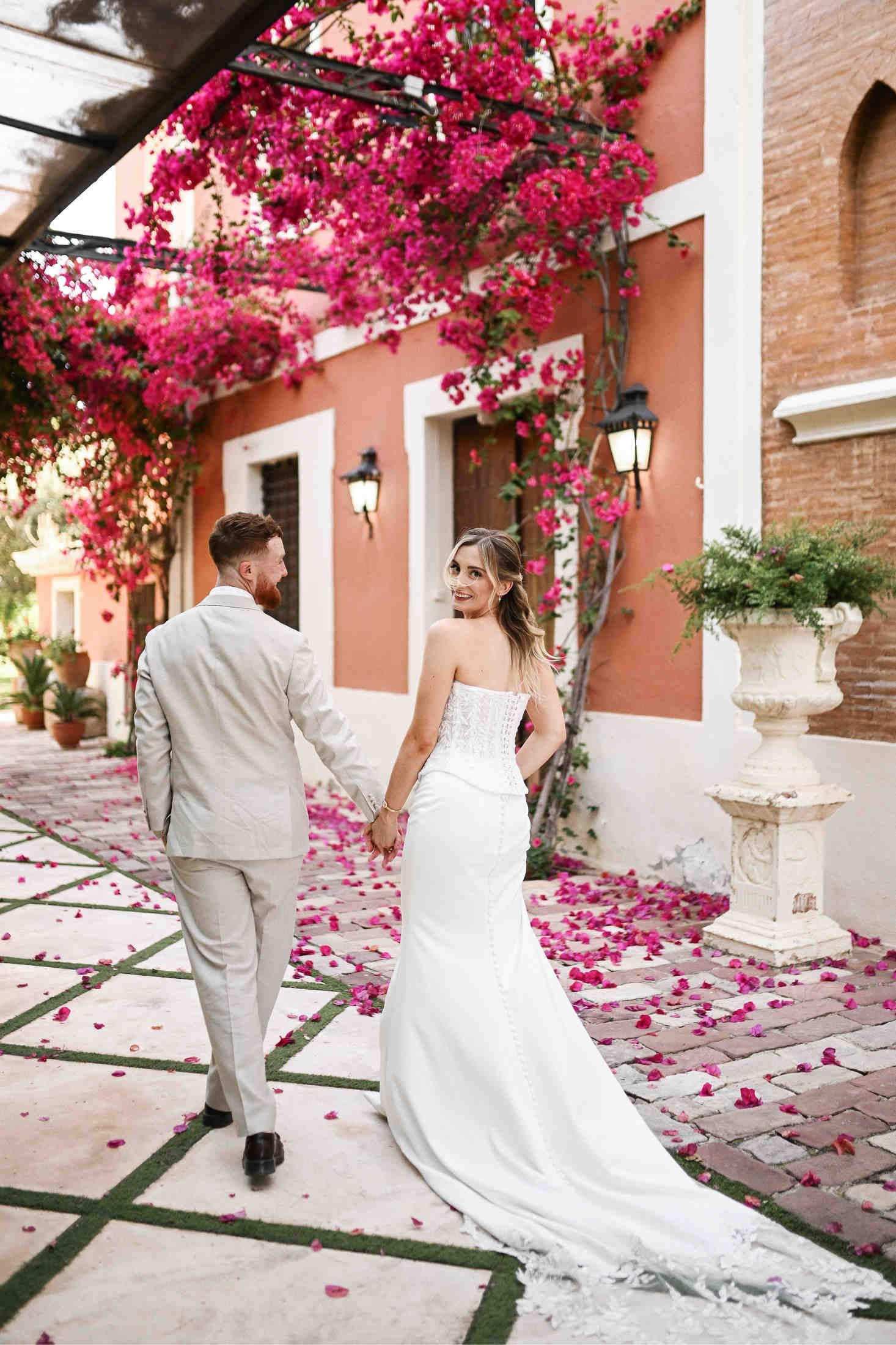 Full-length portrait of a bride in wedding dress and groom against the luxury historic facade of Villa Dela in Valencia