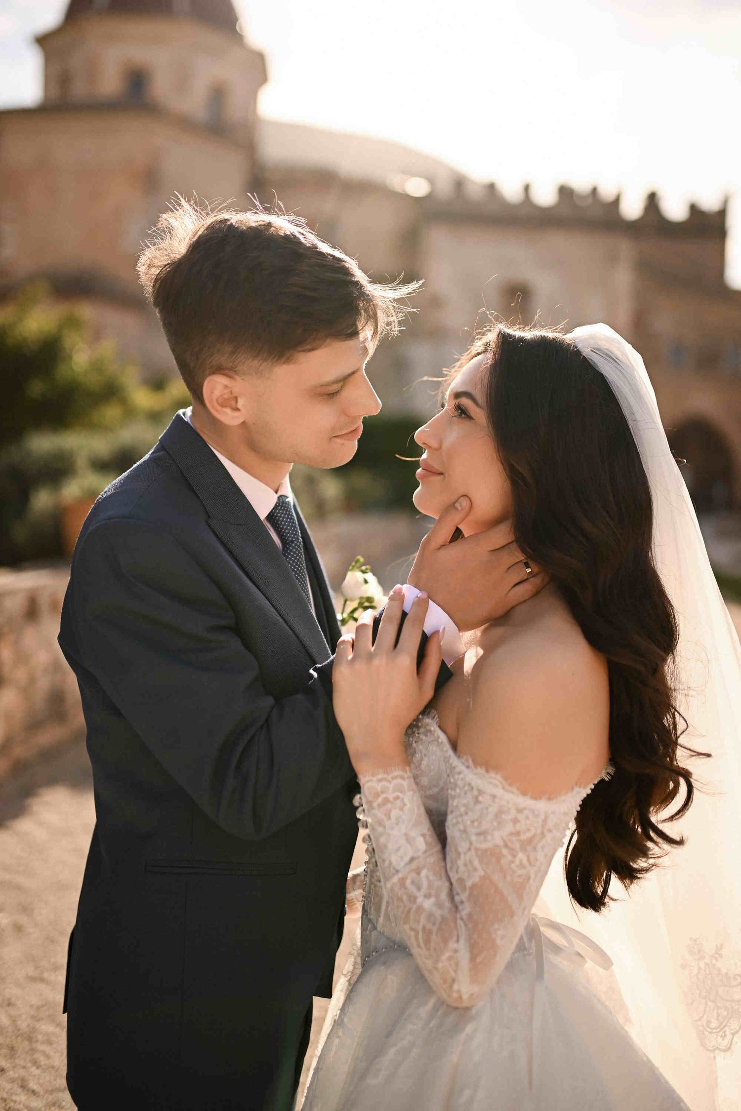 Intimate wedding portrait of a bride and groom under a delicate veil, capturing a tender moment in a historic Spanish monastery setting.