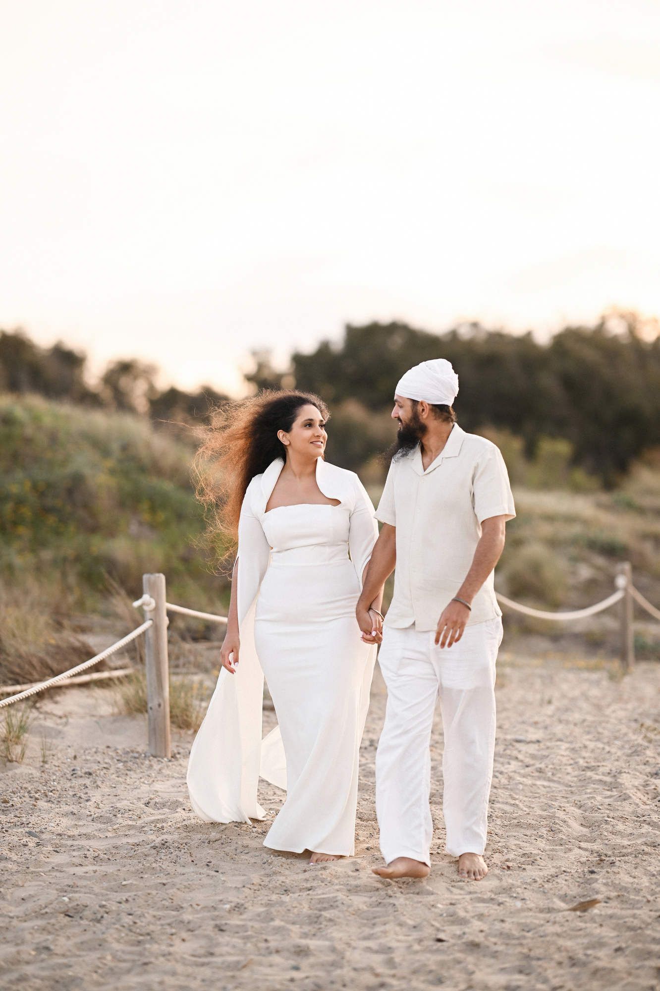 Couple strolling on the sand during golden hour before a surprise marriage proposal - cinematic beach photography and videography