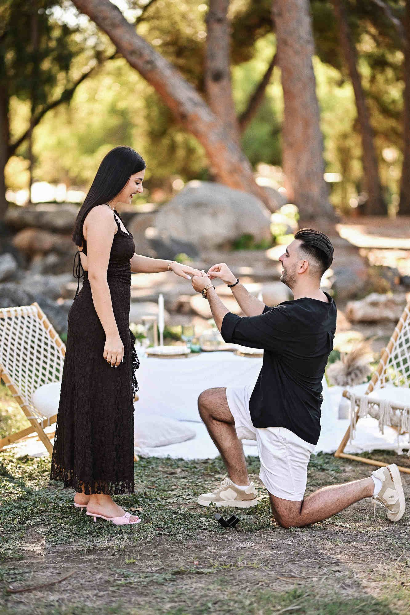 Alin places the engagement ring on Simina's finger during their picnic proposal in Viveros Park