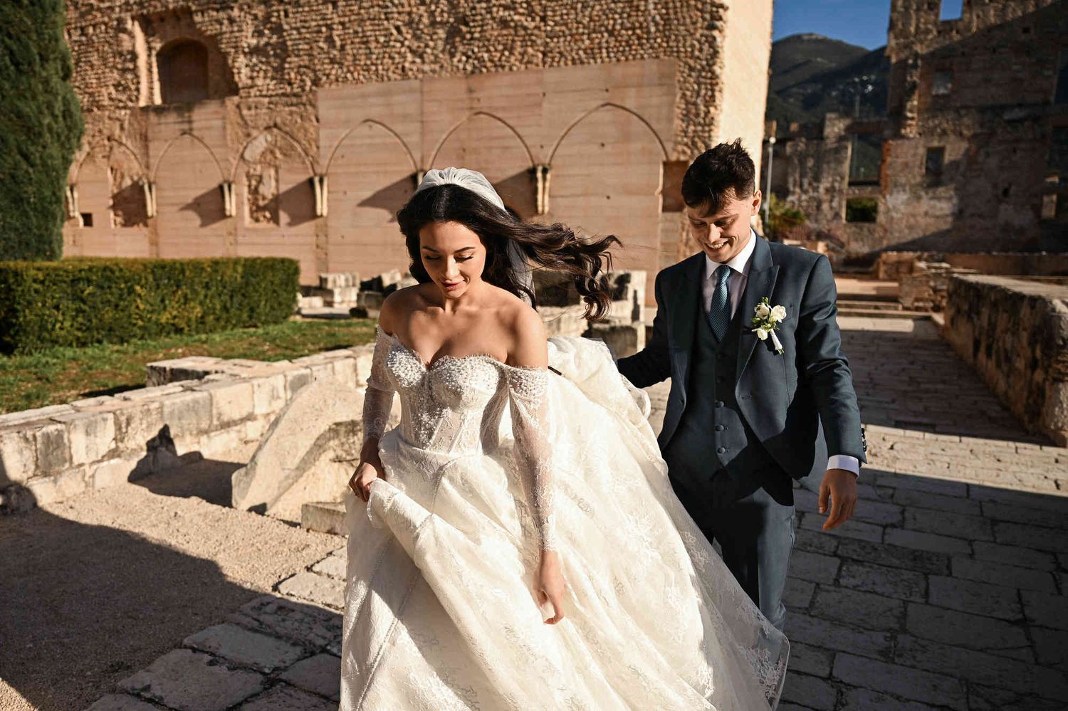 Candid reportage shot of bride and groom walking through the historic grounds of Monasterio de Santa María de la Valldigna, Valencia.