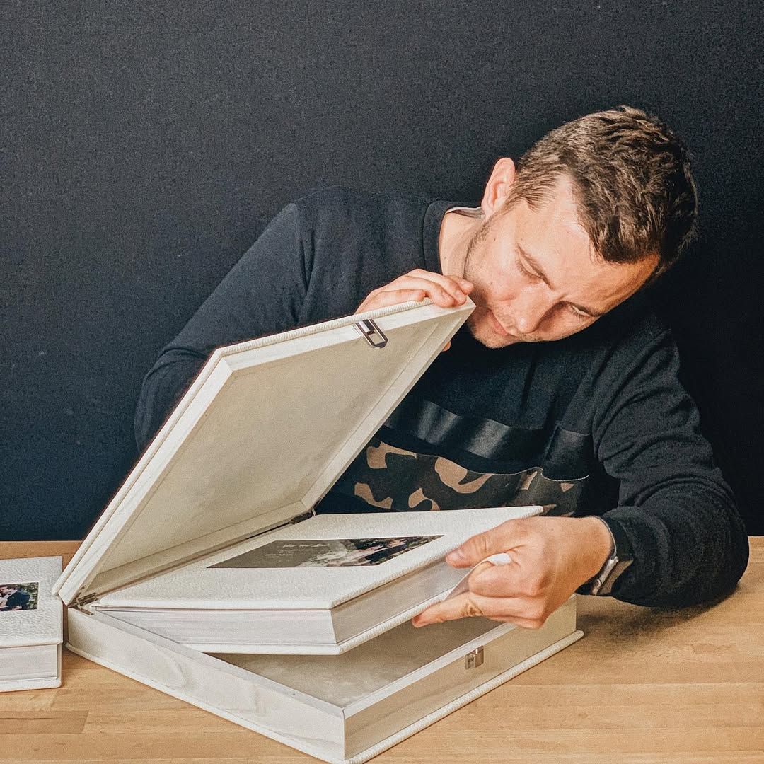 Wedding photographer unboxing premium white leather wedding albums handcrafted for a luxury wedding client in Europe.