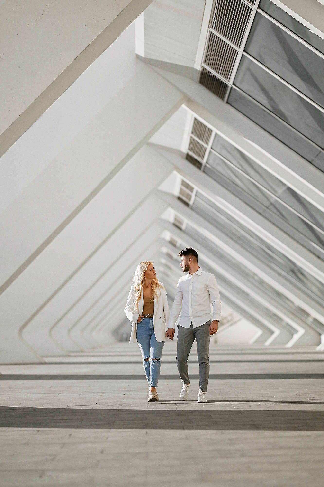 Cinematic shot of a couple holding hands in front of the Calatrava buildings