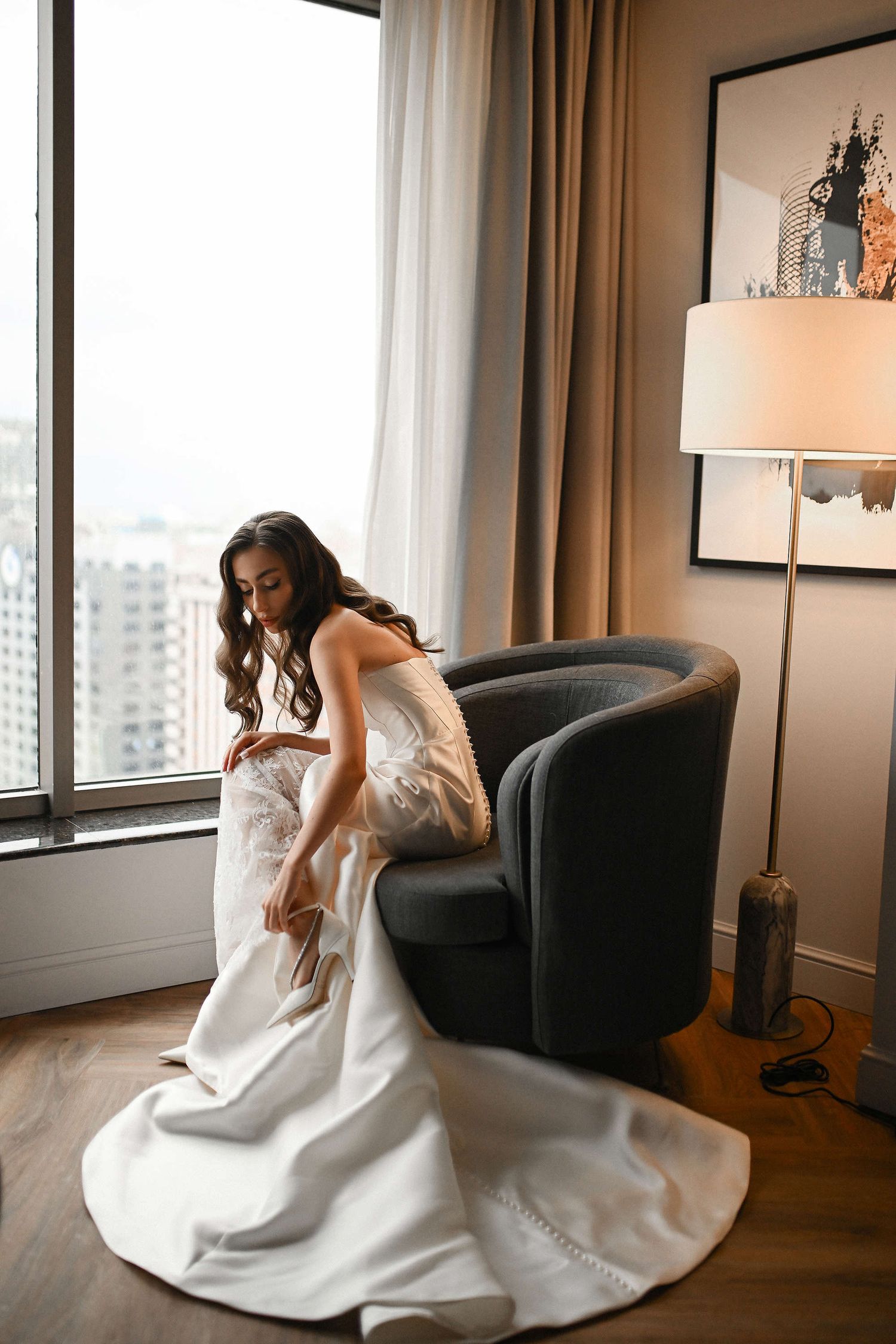 Candid shot of the bride adjusting her shoe buckle, showcasing the elegant train of her wedding dress