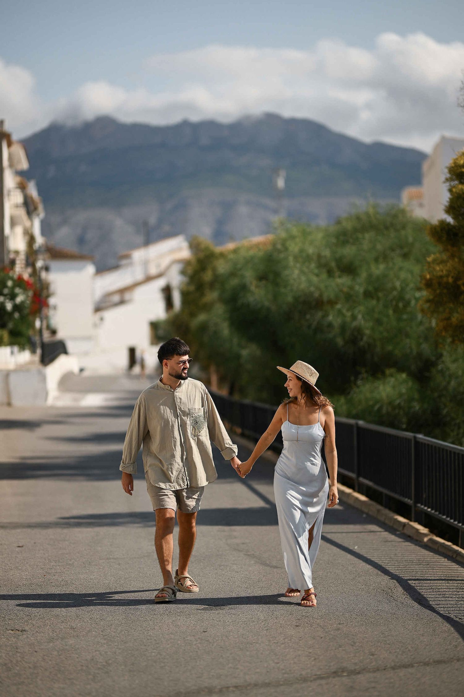 A scenic shot of a couple walking through Altea with the majestic Spanish mountains in the background. Cinematic photography