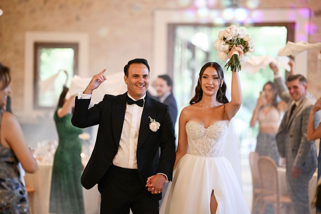 The newlyweds entering the beautiful banquet hall as guests wave white napkins to welcome them, following a lively Spanish tradition.
