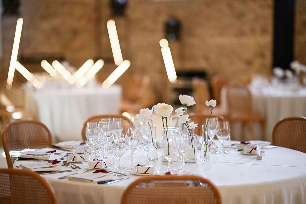 Elegant table setting details and floral centerpieces for a circular arrangement inside the Finca del Canónigo reception hall. Editorial.