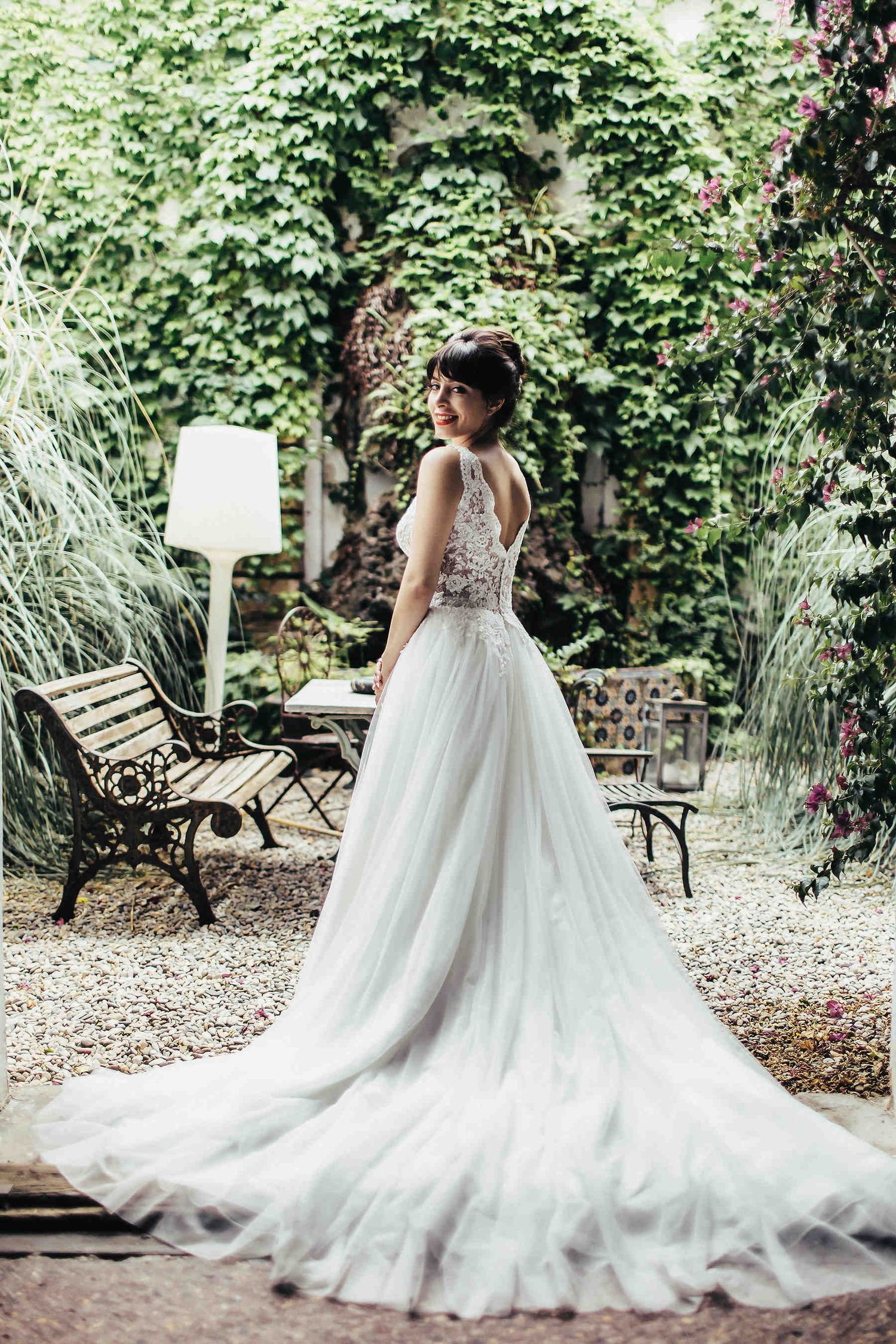 An editorial portrait of the bride with a stunning long dress train in the lush garden of Masia El Follo villa in Catalonia