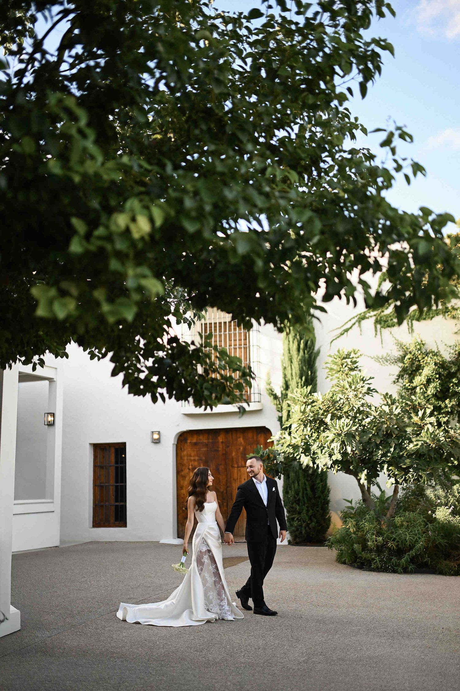 Documentary footage of the bride and groom walking together to the venue of an outdoor Valencian wedding ceremony captured by photographer