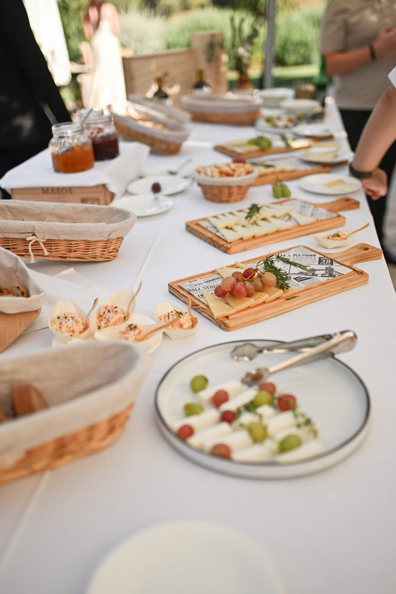 Abundant wedding cocktail buffet with artisanal cheeses, grapes, and bread presented on wooden boards