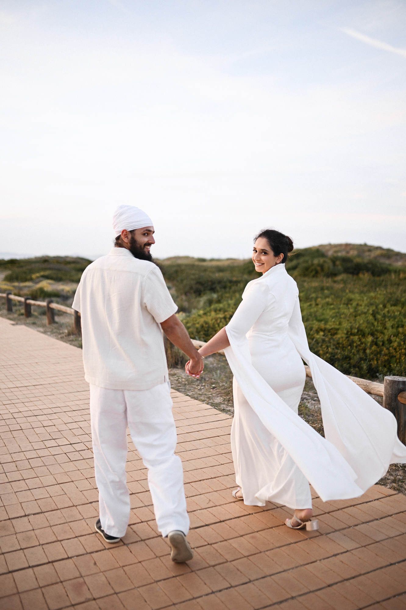 Couple running on a wooden beach bridge in Valencia after a surprise marriage proposal - joyful celebration captured on photo and video