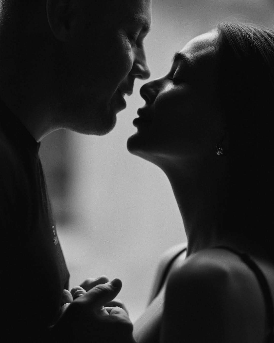 Dramatic black and white love story portrait in Valencia showing the silhouetted profiles of a couple about to kiss.
