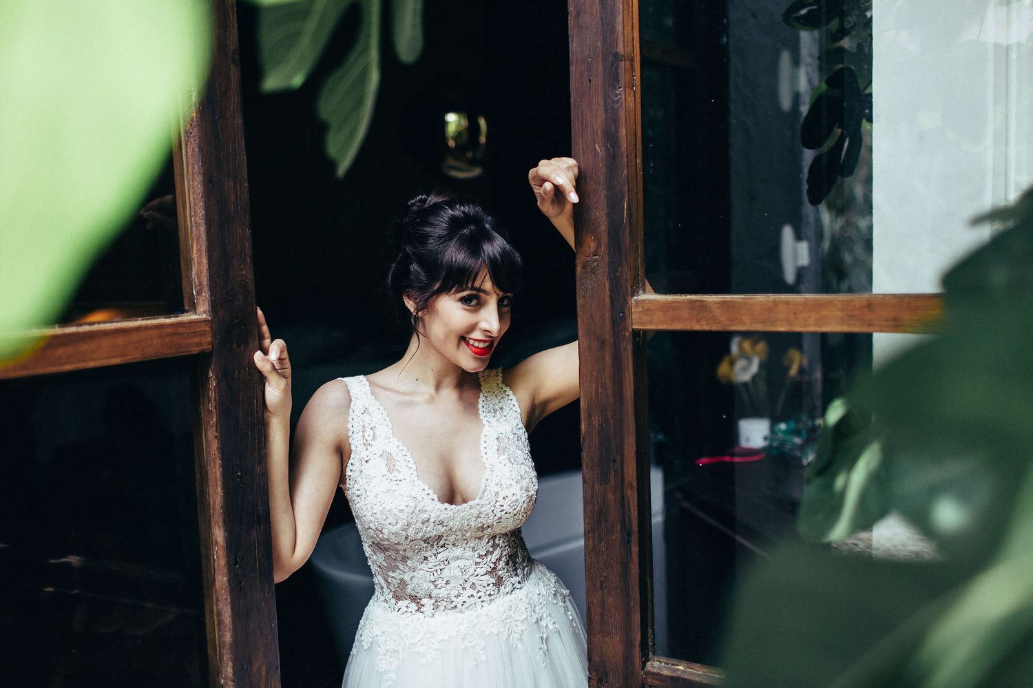 Editorial portrait of a bride leaning on window shutters before her European wedding ceremony, looking at the photographer.
