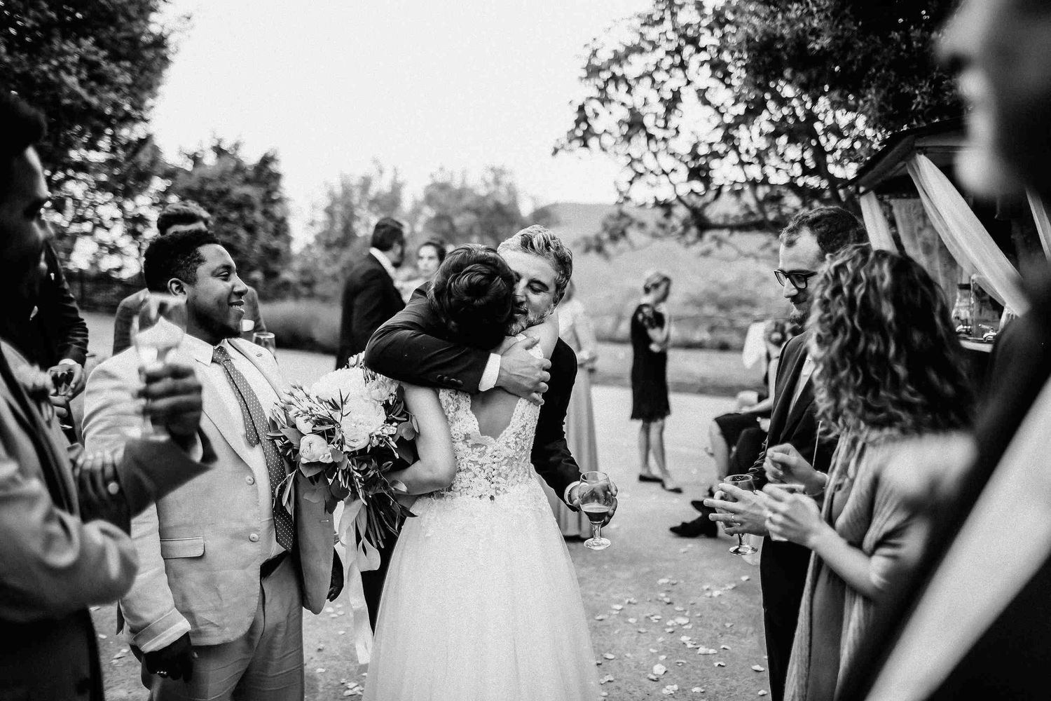 Heartfelt moment of guests hugging bride. Emotional black and white wedding photography in Catalonia, Spain. Real and raw moments - Darista