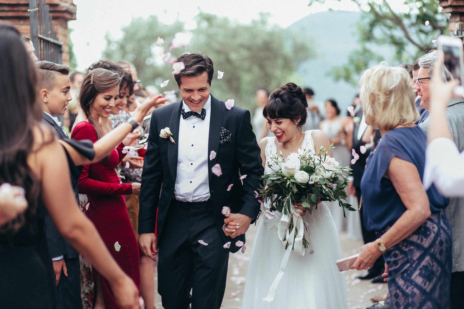 Wedding couple walking through a rose petal toss at a luxury Spanish villa. Capturing the vibrant energy of an iconic European destination.