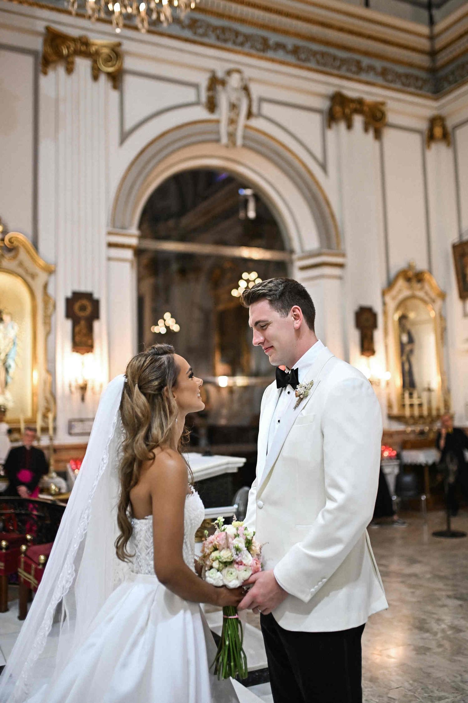 Bride and groom looking lovingly at each other during their wedding ceremony inside a Catholic church.