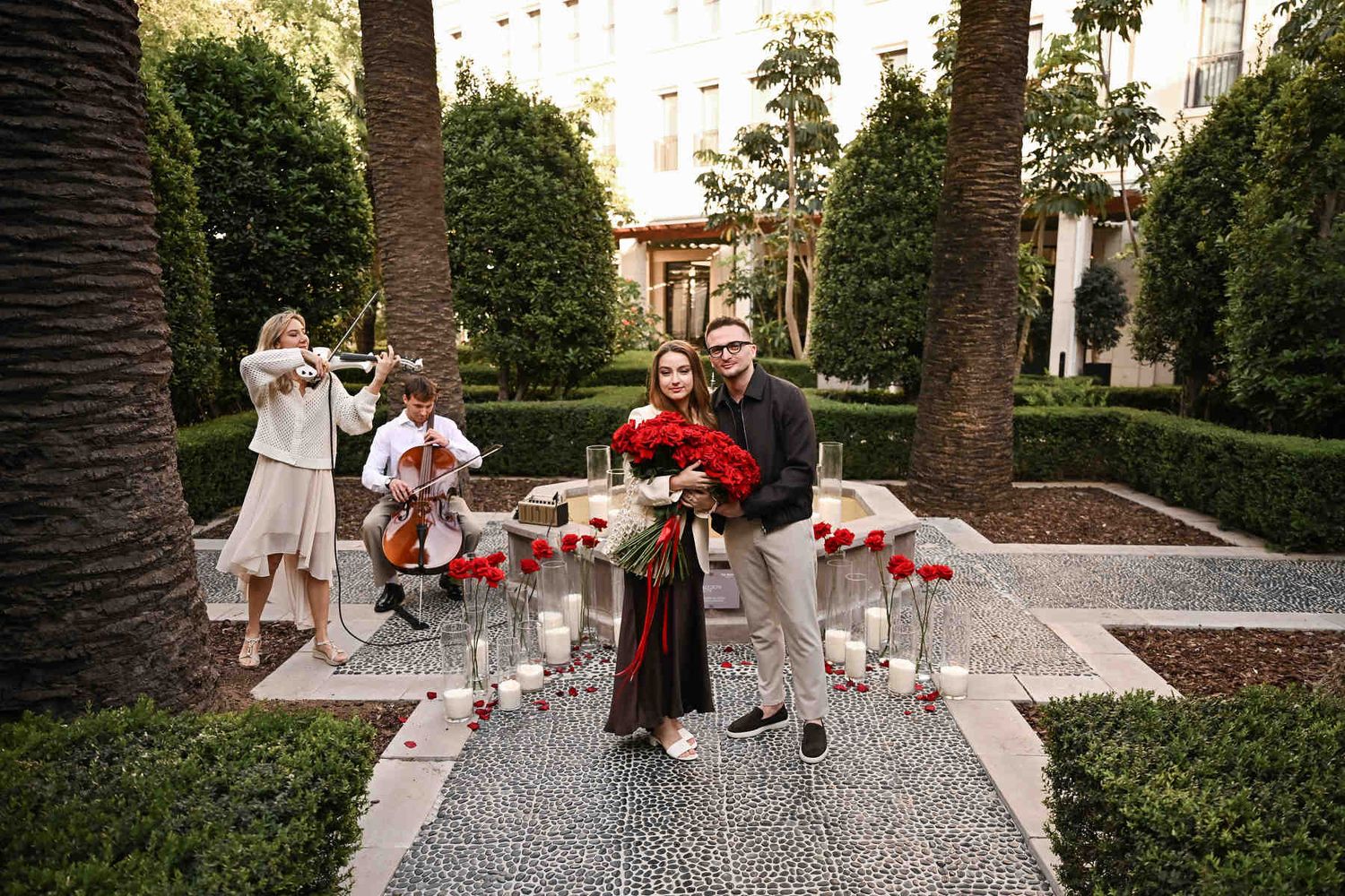 Engaged couple posing near a fountain while live musicians play during their proposal at The Westin Valencia.