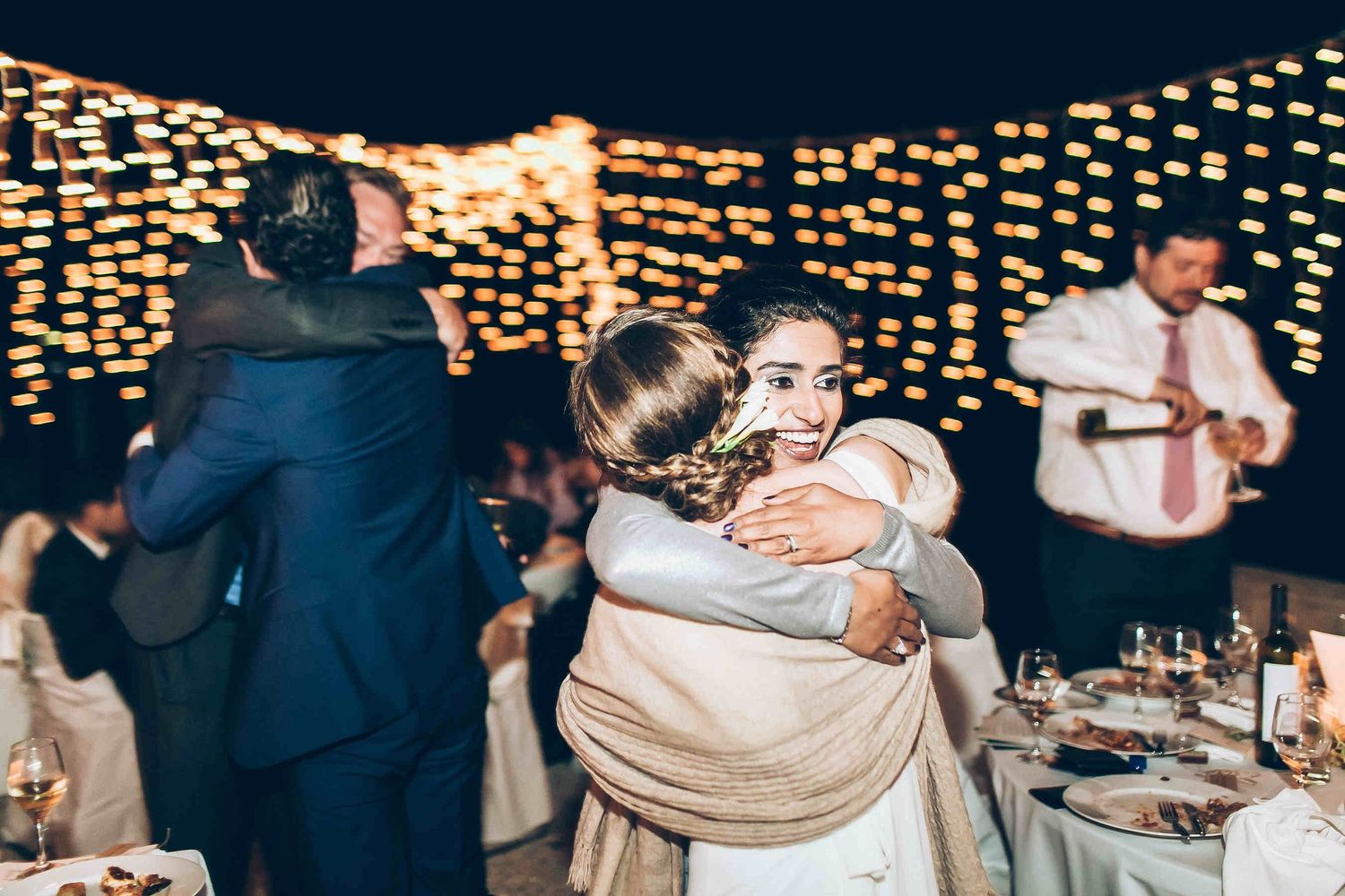 Heartfelt moment of wedding guests embracing the bride during the reception in Milos