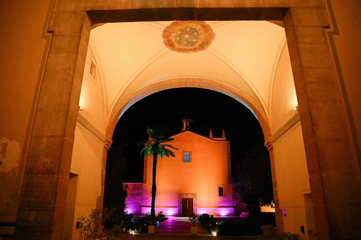 Atmospheric night view of the illuminated La Cartoixa d'Ara Christi monastery during a luxury wedding celebration.