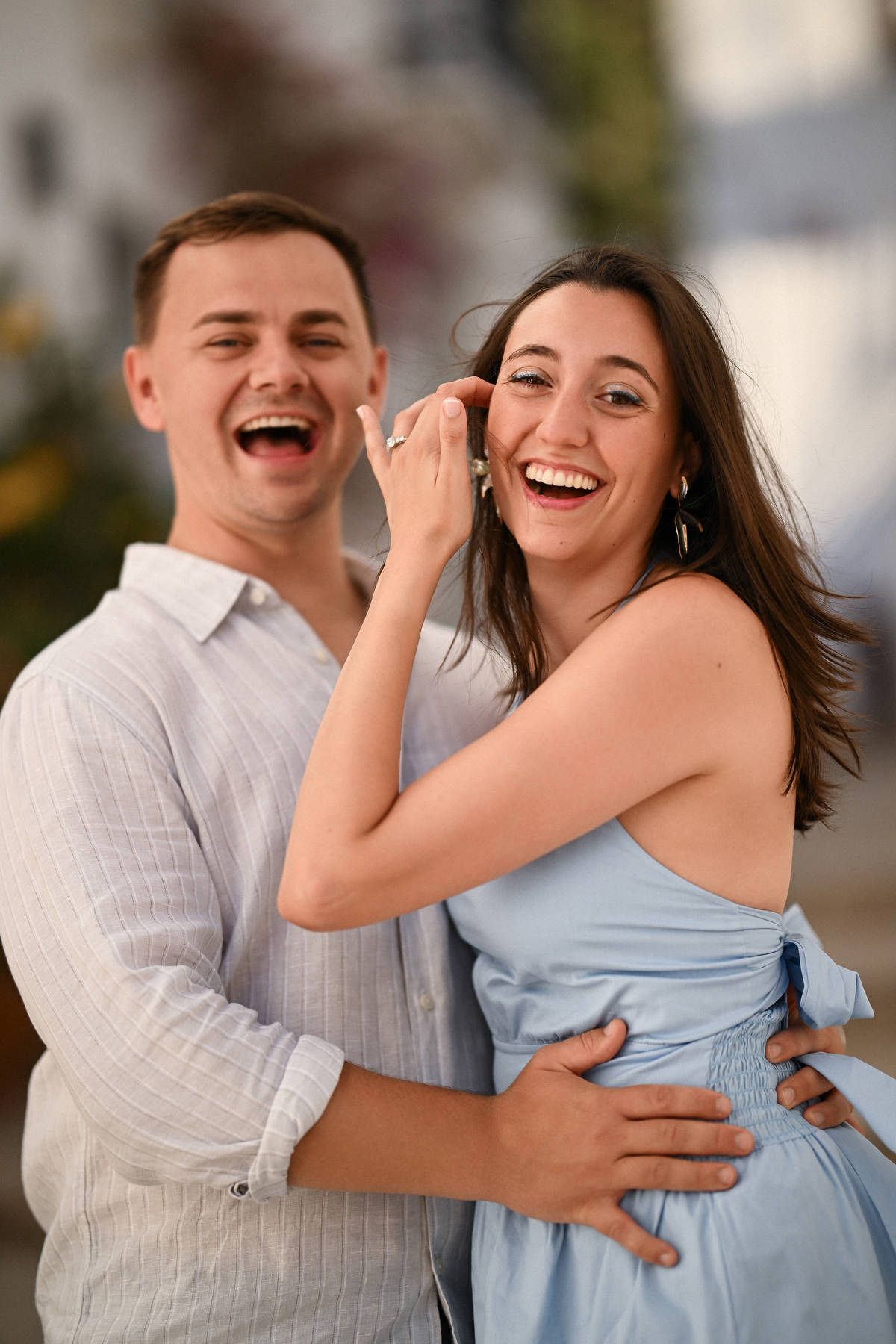 A newly engaged couple laughs joyfully while the woman shows off her ring after a secret proposal in Altea.