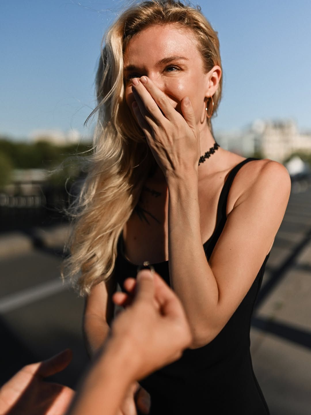 Radiant evening sunlight highlights a woman's shocked reaction during a surprise proposal in Paris as she sees the ring.