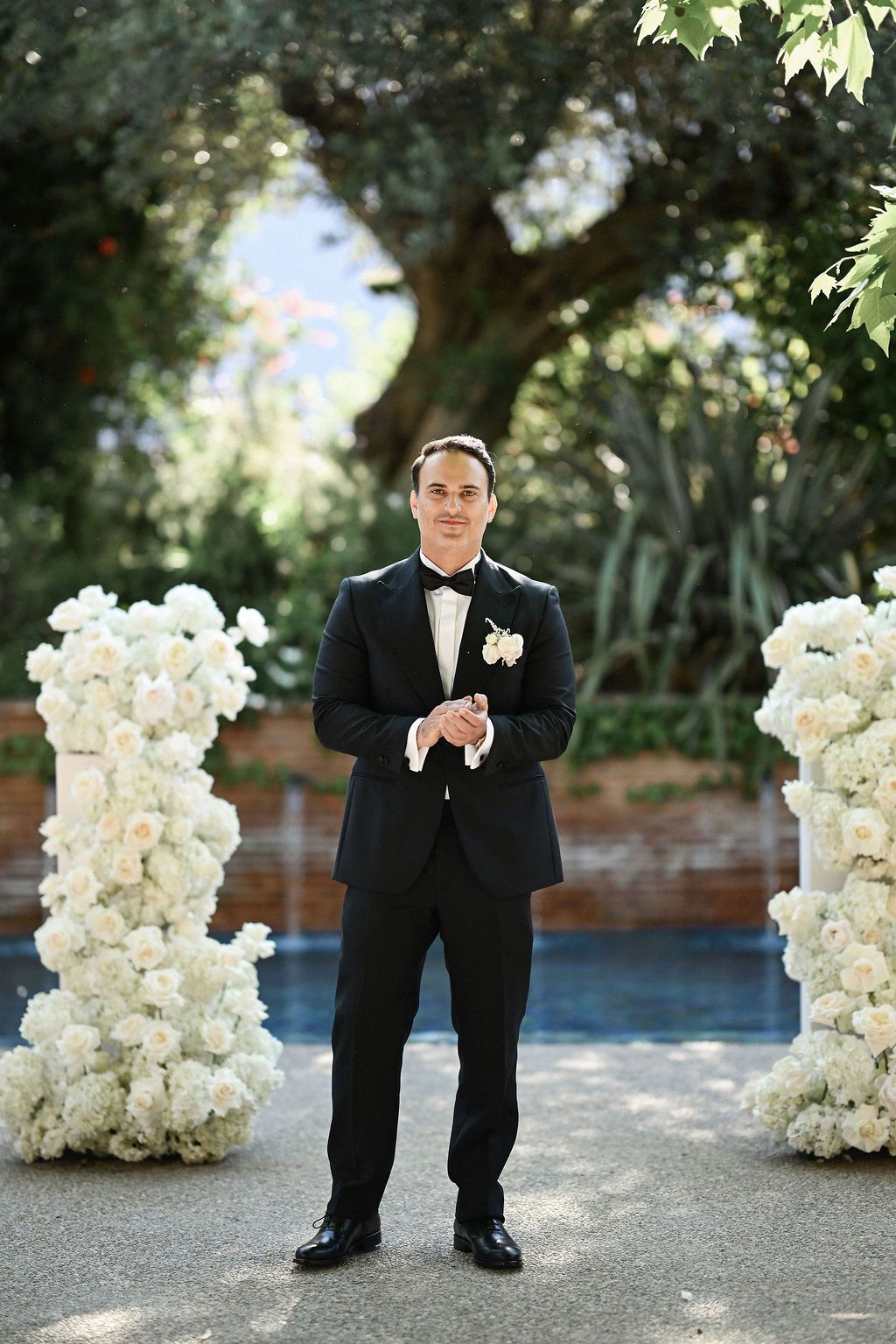 The groom waiting at the floral altar as the father walks the bride down the aisle during a beautiful ceremony at Finca del Canónigo.