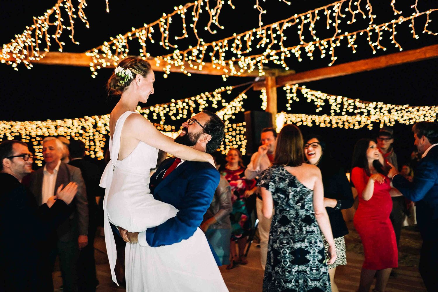 Romantic moment of the bride and groom dancing together under the stars in Milos.Joyful image of the groom lifting his bride in his arms dur