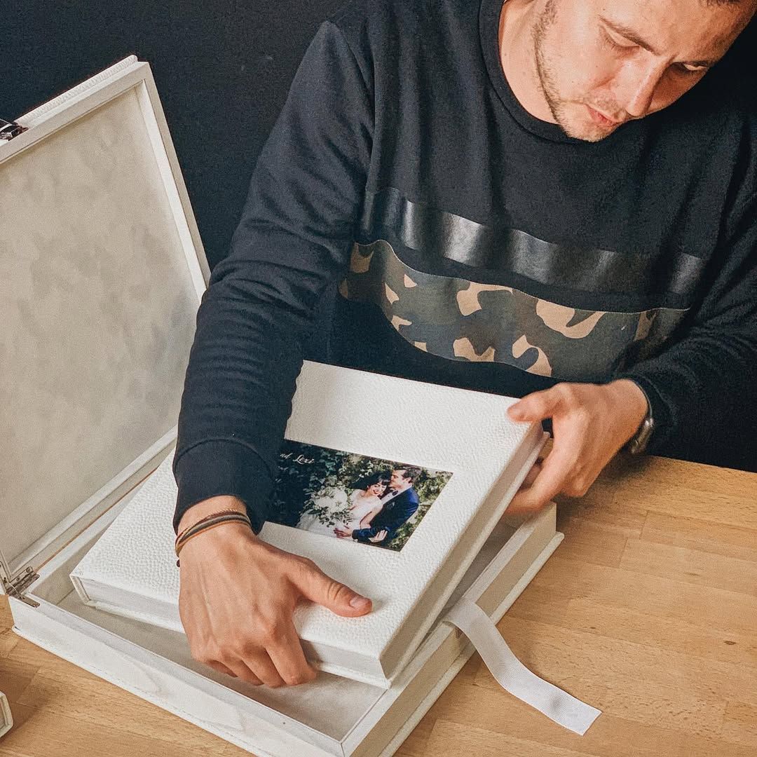 Hands placing a 30x30 leather wedding book into a branded handmade storage box, handcrafted for a premium wedding in Barcelona.