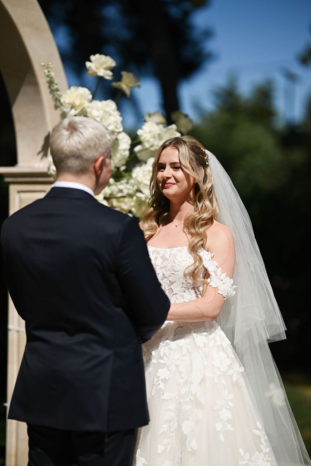 Close-up of the bride and groom holding hands at the historic stone altar during their outdoor destination wedding ceremony in Benidorm.