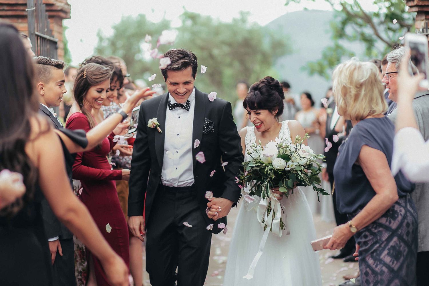 Emotional couple showered with rose petals by guests during a Tagamanent wedding ceremony exit
