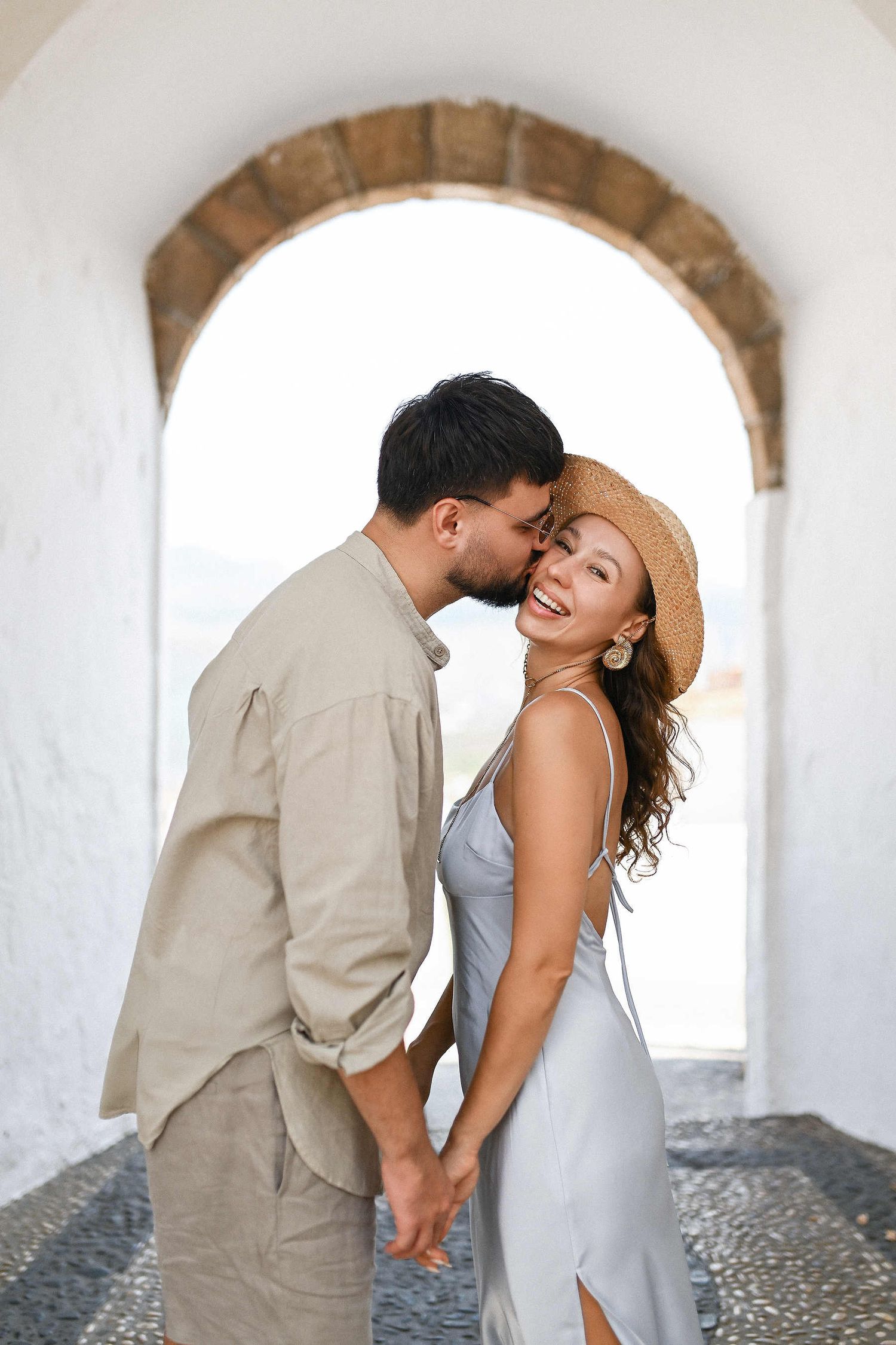 A joyful couple embracing under the historic stone arches of Altea. Timeless cinematic engagement portrait