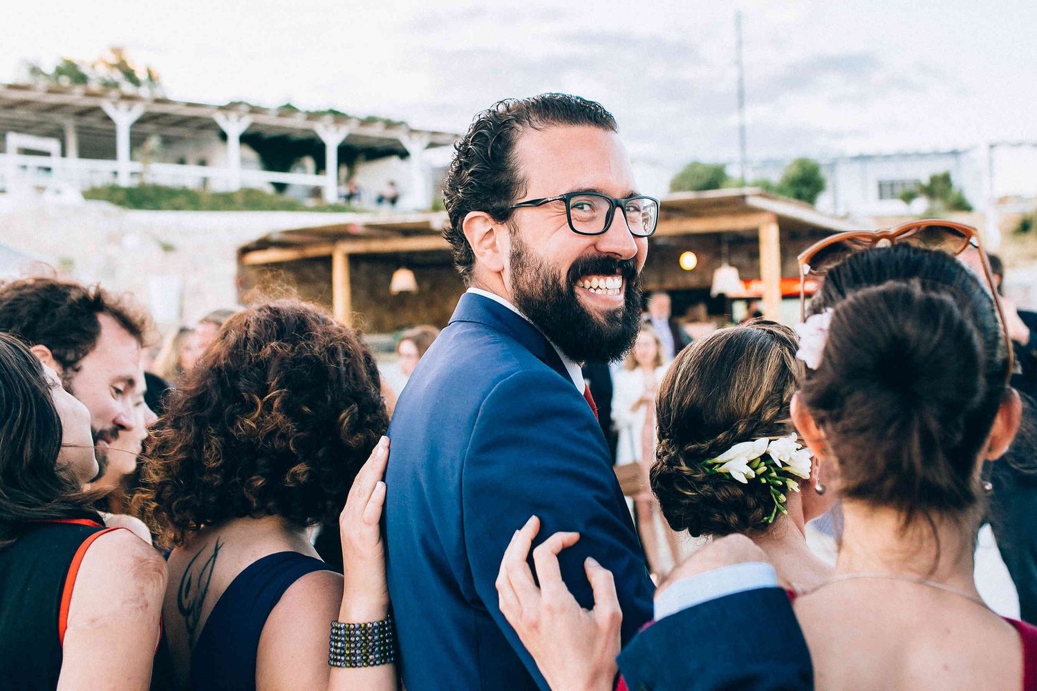 Candid documentary shot of the groom laughing and talking with guests during cocktail hou